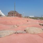 A red landscape with a brick building in the background.