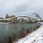 A bridge crossing a river, the riverbanks are covered in a thin layer of snow.