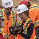 two people in construction outfits look at an iPad