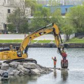 An excavator moving stones in the water