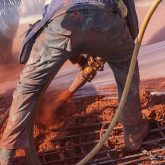 A construction worker spraying red concrete from a hose
