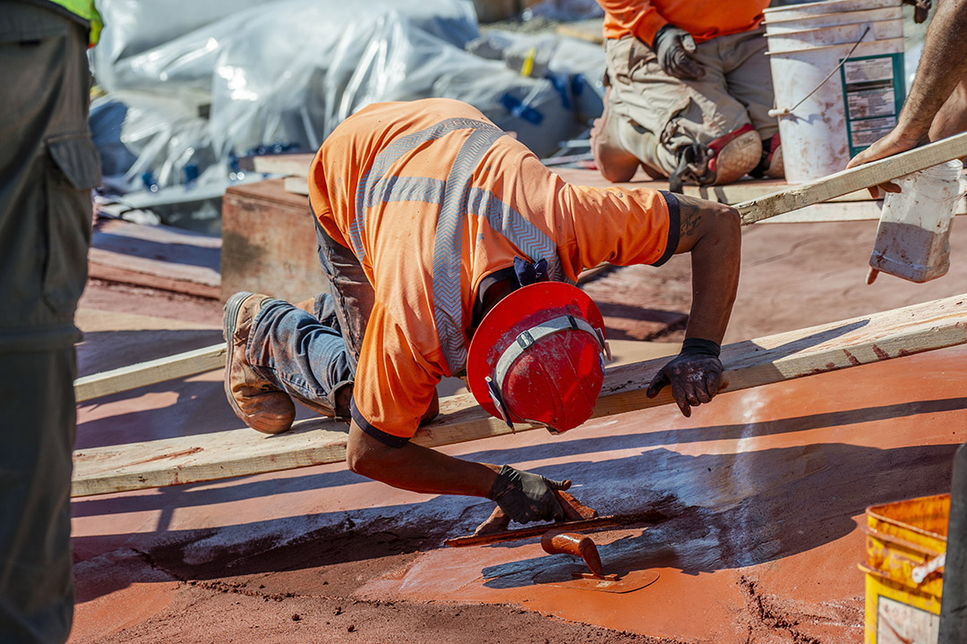 A worker balanced on a 2 by 4 spreading the shotcrete.