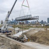 A bike bridge suspended in the air over its foundations.