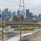 A bike bridge being lowered onto its foundations by a crane.