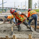 A worker raking concrete.