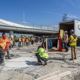 Construction workers measuring something on the ground.