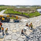 Construction workers standing on a rocky plaza.