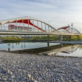 View of a modern bridge over a river situated in a landscaped area with clear skies.