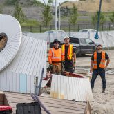 Workers looking up next to the face of the snowy owl structure resting on the ground.