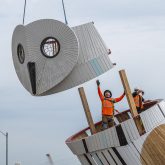 Workers reach for the owls head as it is moved into place above its body.