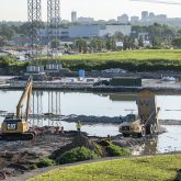 Excavator and dump truck working near water.