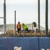 Workers looking at a wooden frame.