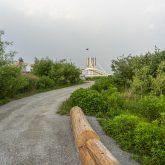 A pathway leading towards a lush green setting with a wooden barrier on one side.
