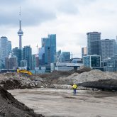 Piles of soil in the foreground, the city of Toronto skyline in the background.