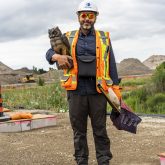 Person holding decoy owl in construction safety gear.