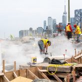 Workers sawing rocks and creating lots of dust.