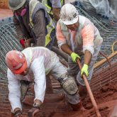 Workers spreading shotcrete on the framing.