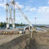 An excavator working in front of a crane.