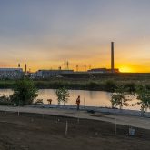 A sunrise over a river with a worker in the foreground.