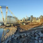 The city of Toronto skyline in the background, with a large white industrial crane in the foreground. Scaffolding is approximately halfway up the crane.