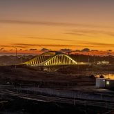 A bridge lit up with the sunrise in the background.