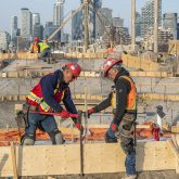 two construction workers hammering a wooden plank