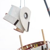 The owl head being lifted by a crane, held over the owls body.