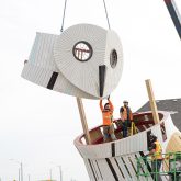 Workers standing on the owls body guide the head into position.