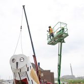 Workers on a lift looking at the owl, now with its head attached.